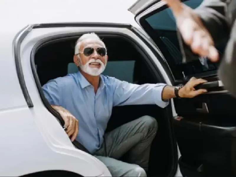 A chauffeur in white gloves holding the door as a passenger steps out of a black SUV